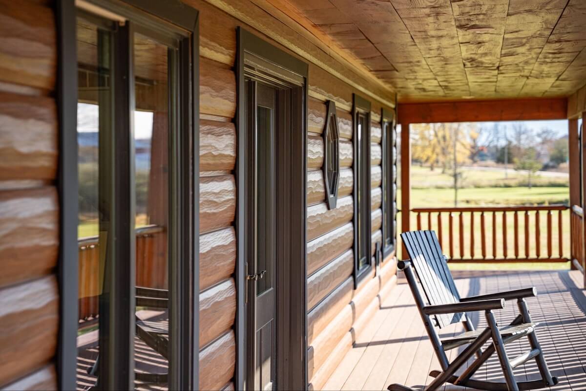 A sunlit porch on a cabin home with TruLog steel faux wood siding