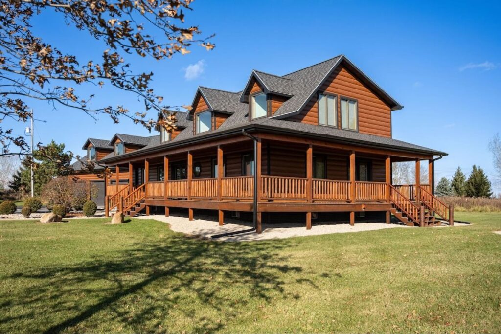 A beautiful home with a wraparound porch that features TruLog steel woodgrain log siding