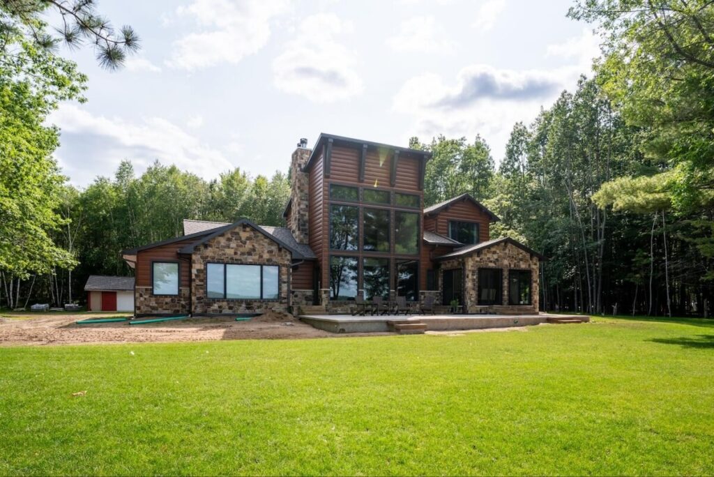 A modern-style home with large windows, stone accents, and TruLog steel log siding