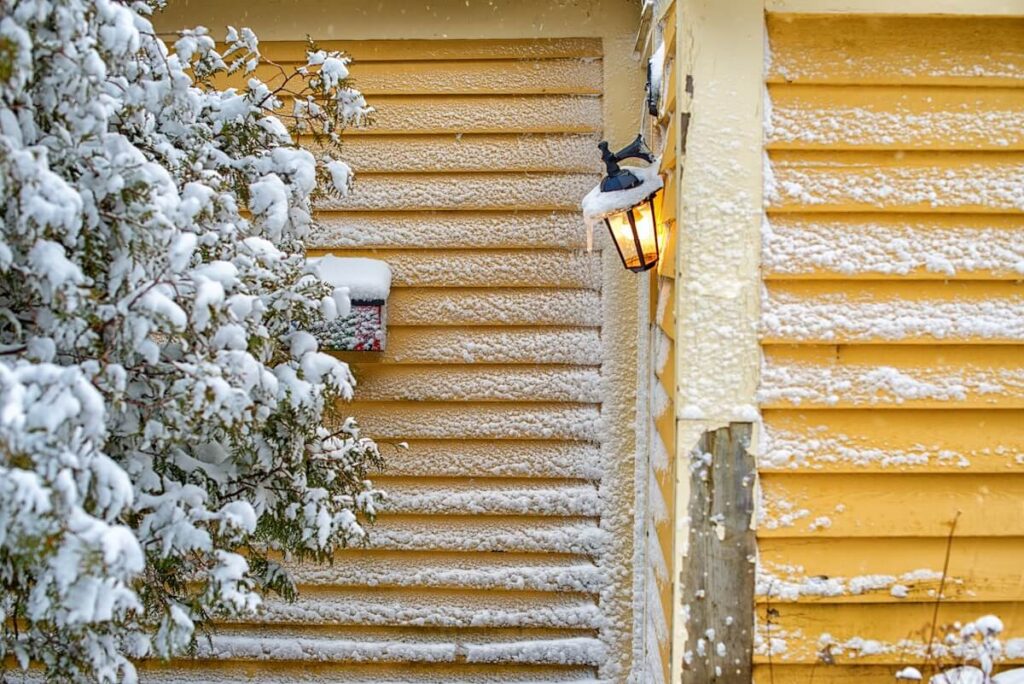 Yellow wood clapboard siding covered in snow