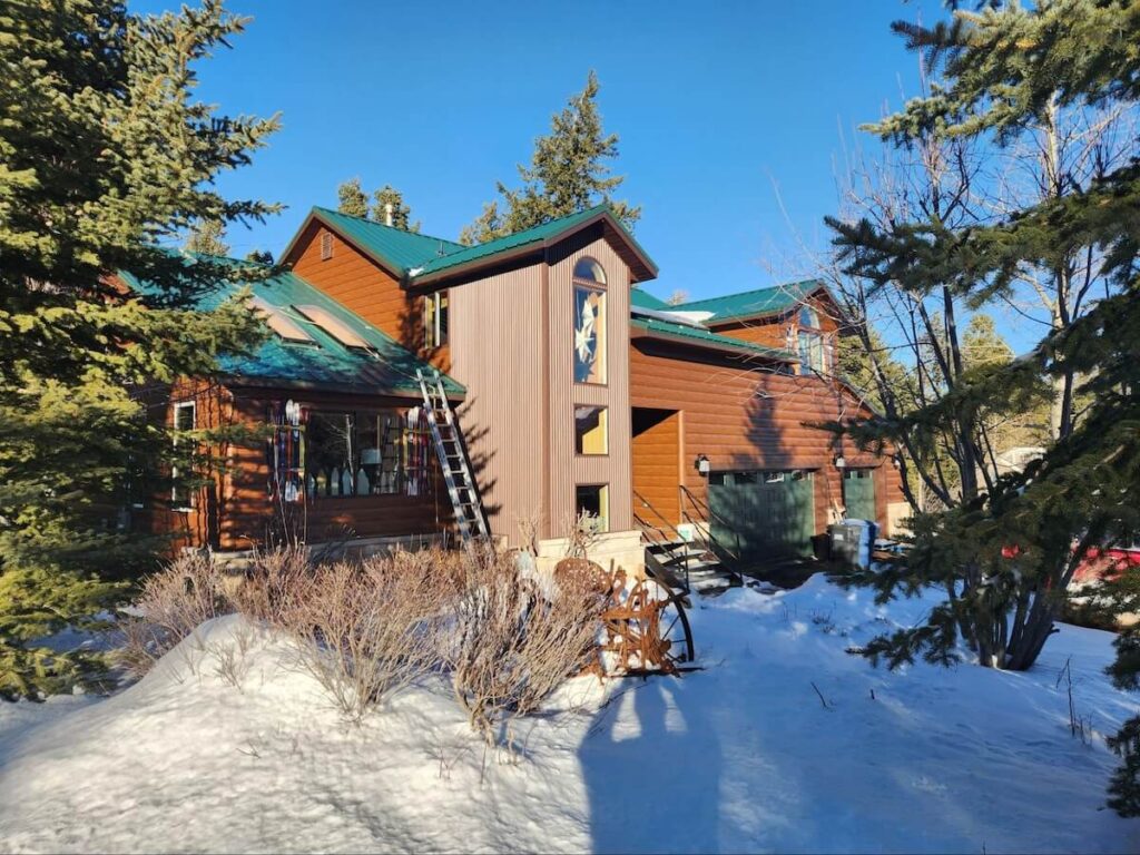 A home featuring insulated TruLog steel log siding and a metal roof during the winter