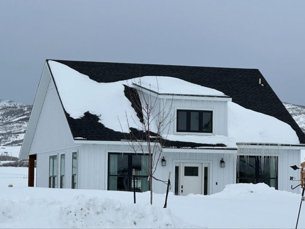A home surrounded by snow that features TruLog steel board and batten siding