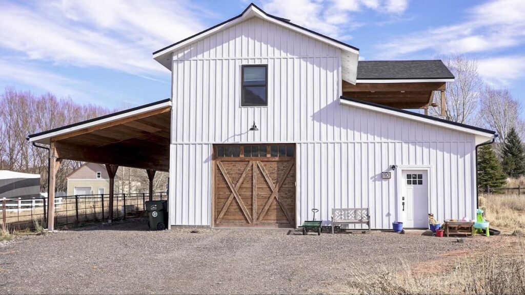 A barndominium with a mix of TruLog steel board and batten siding in Matte White and rustic wood accents