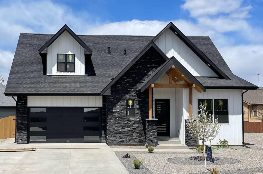 A home with a high-contrast mix of dark stone, TruLog steel board and batten siding in Matte White, and warm wood accents